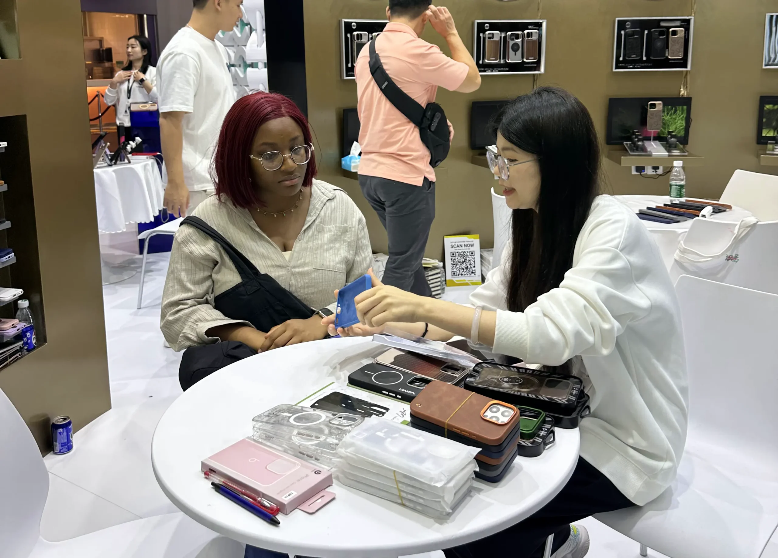 Mobile phone case manufacturers demonstrating sample cases and discussing design options with a visitor at the Hong Kong Global Sources Electronics Show